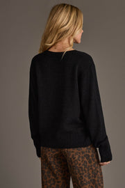 A person with long blonde hair stands with their back to the camera against a plain background, wearing the Black & Tan Game Day Lightweight Sweater from Panache Apparel Collection.