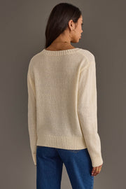 A person with long brown hair, wearing hoop earrings and blue jeans, stands facing away from the camera against a plain gray background while modeling the Ivory Game Day Lightweight Sweater by Panache Apparel Collection.