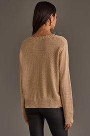 A woman with long dark hair, seen from behind, is wearing the Panache Apparel Collection's Tan Game Day Lightweight Sweater paired with black pants. The background is plain and neutral.