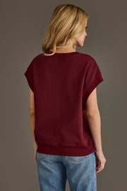 A woman with long blonde hair, wearing the Panache Apparel Collection Maroon & Gold Game Day Short Sleeve Sweatshirt and blue jeans, stands facing away against a plain gray background.