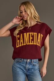 A woman with long blonde hair wears the Maroon & Gold Game Day Short Sleeve Sweatshirt by Panache Apparel Collection, featuring large yellow "GAMEDAY" lettering, paired with blue jeans and standing against a plain background.