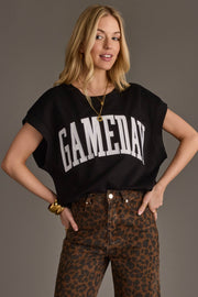 A woman with long blonde hair stands with her hands on her hips against a neutral background, wearing the Panache Apparel Collection Black & White Game Day Short Sleeve Sweatshirt paired with gold jewelry and high-waisted leopard print pants.