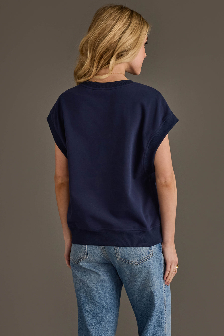 A person with blonde hair wears the Panache Apparel Collection Navy & Red Game Day Short Sleeve Sweatshirt and light blue jeans, standing with their back to the camera against a plain background.