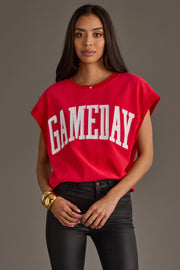 A woman with long dark hair wears the Panache Apparel Collection Red & White Game Day Short Sleeve Sweatshirt, paired with black pants, gold bracelets, and rings, standing against a plain gray background.