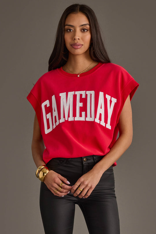 A woman with long dark hair wears the Panache Apparel Collection Red & White Game Day Short Sleeve Sweatshirt, paired with black pants, gold bracelets, and rings, standing against a plain gray background.