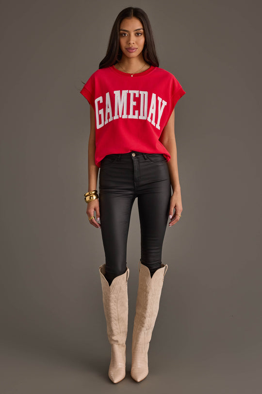 A woman stands against a plain gray background wearing the Panache Apparel Collection Red & White Game Day Short Sleeve Sweatshirt, black skinny jeans, tan cowboy boots, and gold bracelets.