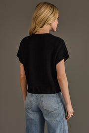 A person with blonde hair wears the Panache Apparel Collection's Black & White Game Day Short Sleeve Sweater paired with light blue jeans, standing against a plain grey background and facing away from the camera.