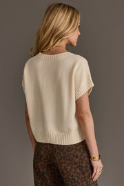 A woman with long blonde hair, seen from behind, wears the Panache Apparel Collection Ivory Short Sleeve Sweater paired with high-waisted brown leopard print pants. She is standing against a plain gray background.
