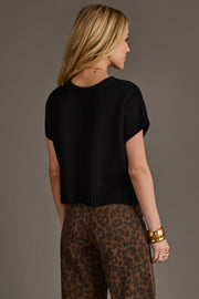 A woman with long blonde hair is seen from behind, standing against a plain background, wearing the Panache Apparel Collection Black Short Sleeve Sweater paired with brown leopard print pants.