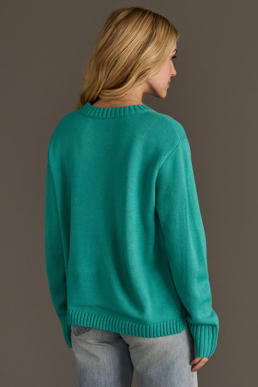A person seen from the back wearing a bright turquoise long-sleeved knit Light Blue & Bright Pink Merry Sweater.