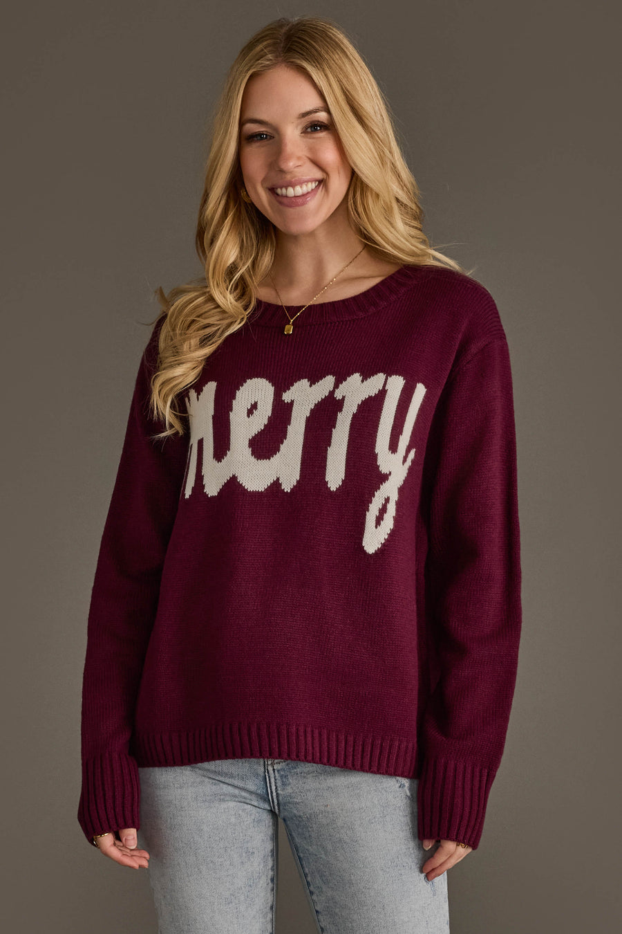 A smiling woman wears a burgundy Wine Merry Sweater by Panache Apparel Collection featuring the word merry in white script across the chest.