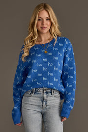 A woman wearing a Blue Ho Ho Ho Sweater, a blue long-sleeve top featuring a repeating white ho pattern.