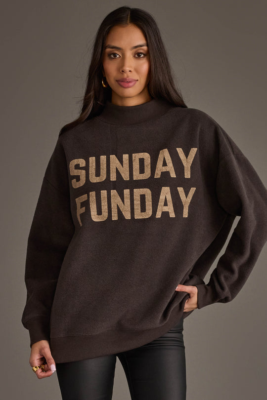 A woman with long, dark hair stands against a gray background, wearing the Panache Apparel Collection’s Dark Gray Game Day & Sunday Funday Reversible Sweatshirt. She looks at the camera with a relaxed expression, showcasing the bold "SUNDAY FUNDAY" lettering on the front.