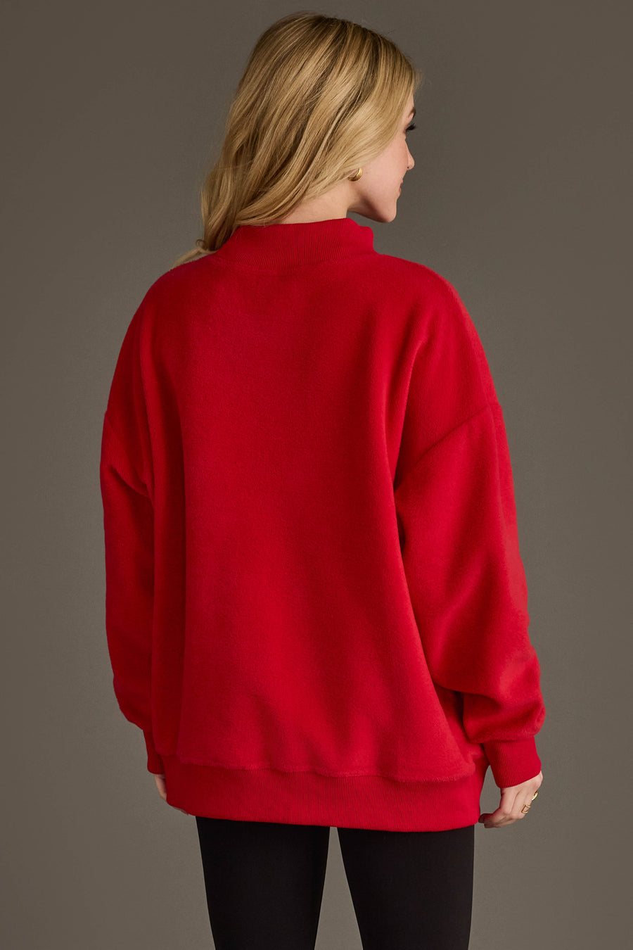 A person with long blonde hair, seen from behind, wears the Panache Apparel Collection's Red Game Day & Sunday Funday Reversible Sweatshirt and black leggings, standing against a plain grayish-brown background.