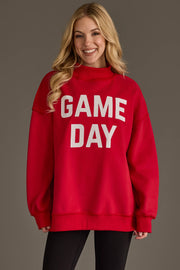 A smiling woman with long blonde hair wears the Panache Apparel Collection's Red Game Day & Sunday Funday Reversible Sweatshirt, paired with black pants, standing against a plain gray background.