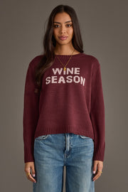 A person wearing the Panache Apparel Collection Burgundy & Light Pink Wine Season Sweater, paired with blue jeans, stands against a plain gray background.