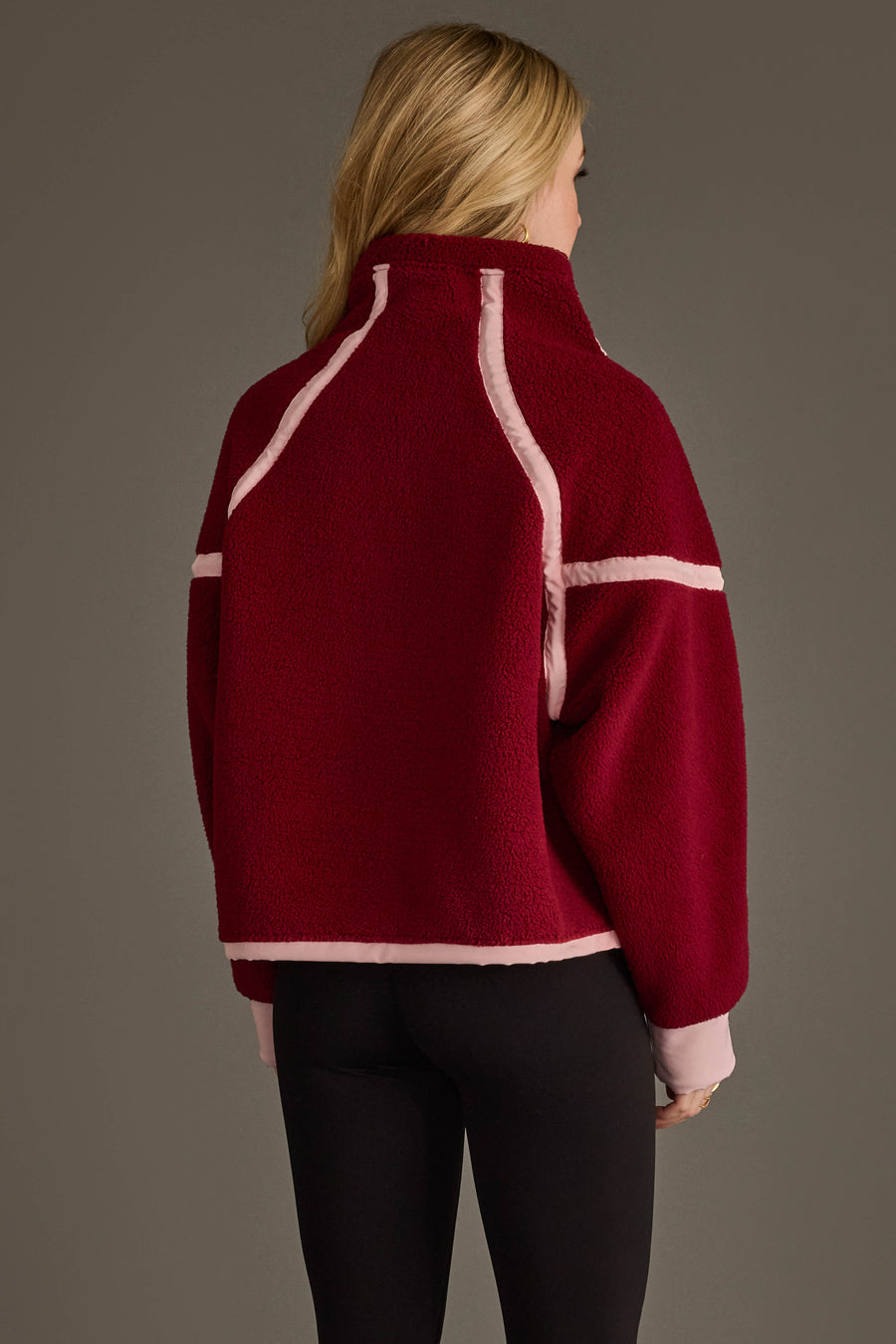 A person with long blonde hair, shown from the back against a plain background, is wearing the Panache Apparel Collection Burgundy & Light Pink Half Zip Sherpa Fleece Sweatshirt and black pants.