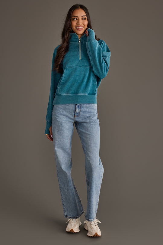 Full-length woman modeling Panache Apparel’s dark teal quarter zip sweatshirt.