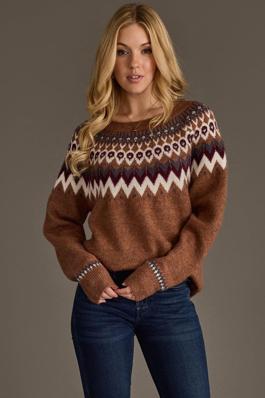 Blonde model wearing Panache Apparel’s brown, gray, burgundy and white Fair Isle sweater with a crew neckline and long sleeves.