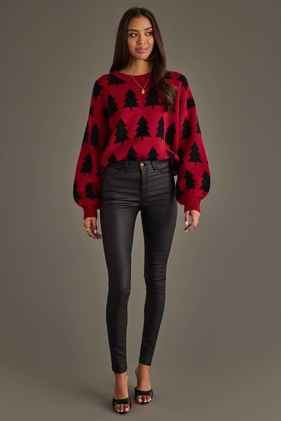 A woman wearing a Panache Apparel Collection Red & Black Tree Sweater with a black Christmas tree pattern and black skinny pants.