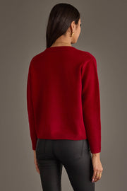 A person viewed from behind wearing a red Home For The Holidays Soft Sweater and dark pants.