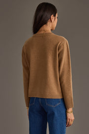 A woman faces away from the camera, wearing the Tan Soft Sweater by Panache Apparel Collection paired with blue jeans, large hoop earrings, and gold bracelets. Her dark hair is worn down as she poses against a plain, neutral background.