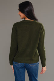 A person with long dark hair models the Panache Apparel Collection's Dark Green Soft Sweater, paired with blue jeans, standing facing away from the camera against a plain gray background.