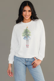 A woman wearing a white Girl With Christmas Tree Sweatshirt from the Panache Apparel Collection, featuring an illustration of a person holding a Christmas tree and wearing red shoes.