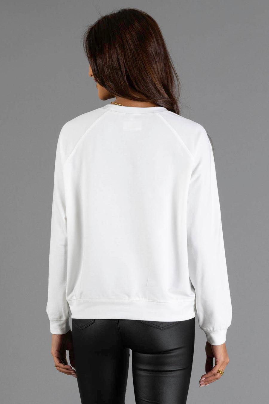 A person with long brown hair, wearing the Panache Apparel Collection Halloween Girls Sweatshirt and black pants, is standing with their back to the camera against a plain gray background.