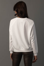 A person stands facing away against a plain gray background, wearing the Panache Apparel Collection’s “Girl Walking a Turkey Sweatshirt” in white long sleeves and dark leather pants.
