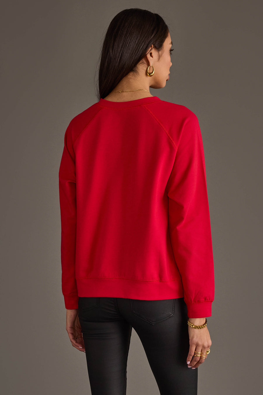 A person seen from the back wearing a plain red long-sleeved Tis The Season To Be Jolly Sweatshirt and black pants.
