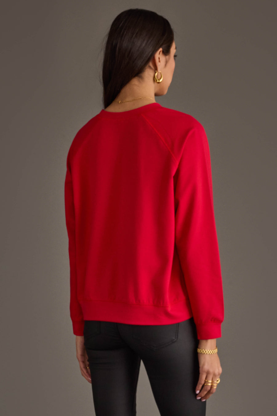 A person viewed from behind, wearing an oversized red Feelin Jolly Sweatshirt and black pants.