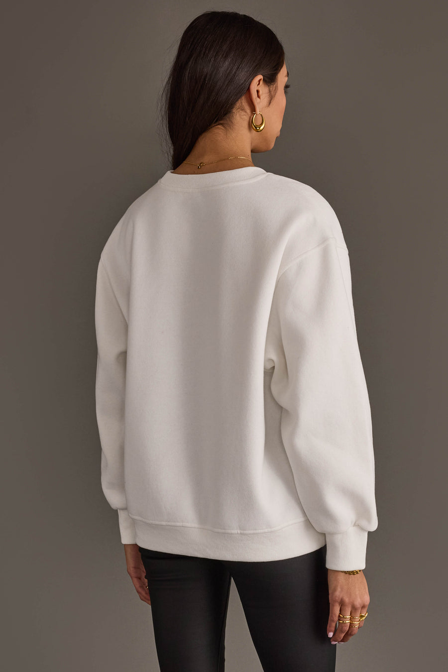 A person seen from the back wearing a white Giddy Up Jingle Horse Sweatshirt and black pants.