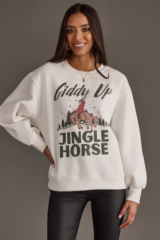 A smiling woman wears an off-white Panache Apparel Collection Giddy Up Jingle Horse Sweatshirt featuring a graphic of a person riding a horse and the text Giddy Up Jingle Horse.