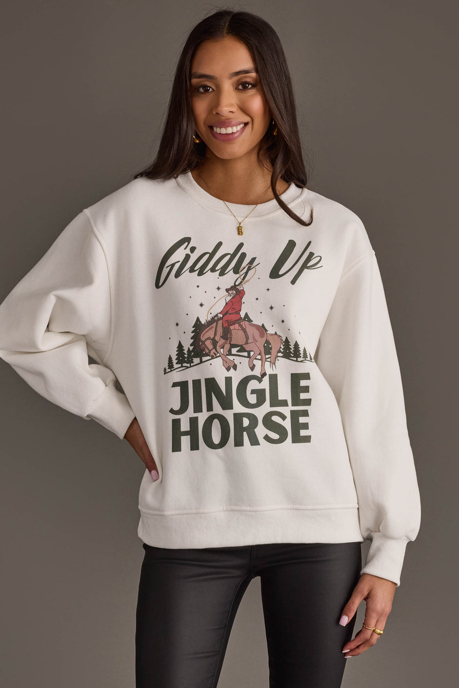 A smiling woman wears an off-white Panache Apparel Collection Giddy Up Jingle Horse Sweatshirt featuring a graphic of a person riding a horse and the text Giddy Up Jingle Horse.