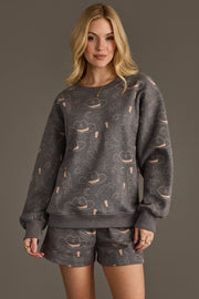 Woman wearing Panache Apparel’s charcoal western print sweatshirt and shorts set.