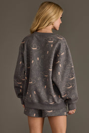 Back view of woman wearing Panache Apparel’s charcoal western print sweatshirt and shorts set.