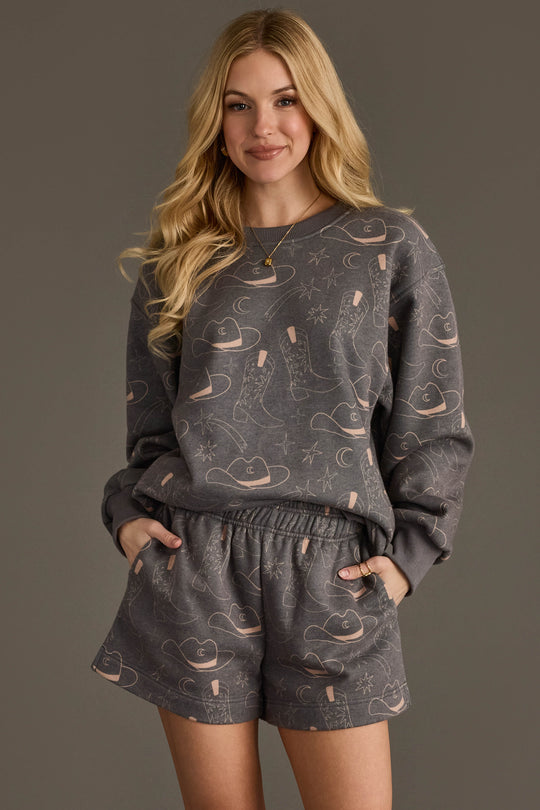 Woman wearing Panache Apparel’s charcoal western print sweatshirt and shorts set.