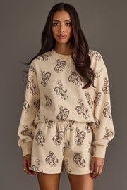 Woman wearing Panache Apparel’s ivory western print sweatshirt and lounge shorts set.