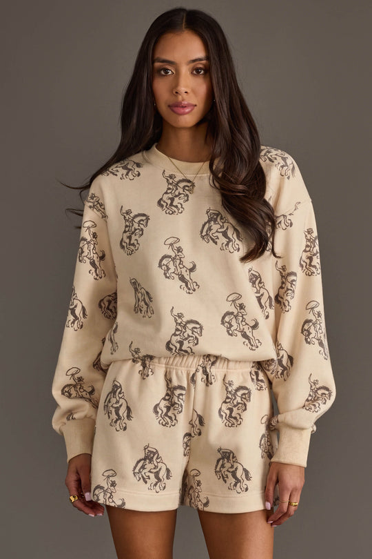 Woman wearing Panache Apparel’s ivory western print sweatshirt and lounge shorts set.