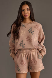 Woman wearing Panache Apparel’s dusty rose western print sweatshirt and lounge shorts set.