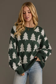 A woman wearing a Green & White Tree Sweater with a white repeating pine tree pattern and light-wash jeans.