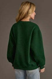 A person seen from behind wearing a plain dark green Green Merry Little Cocktail Embroidered Sweatshirt.