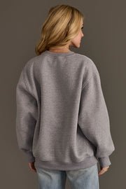 Back view of a person wearing a cozy, plain grey You Be Merry Embroidered Sweatshirt.