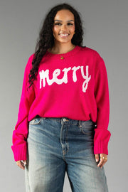 A person wears a relaxed fit, bright pink Pink & Light Pink Merry Sweater with the word merry written in white script across the chest.