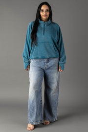 Full-length plus-size woman modeling a dark teal quarter zip sweatshirt.