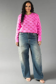 A person wearing a bright pink Pink Ho Ho Ho Sweater and wide-leg blue jeans.