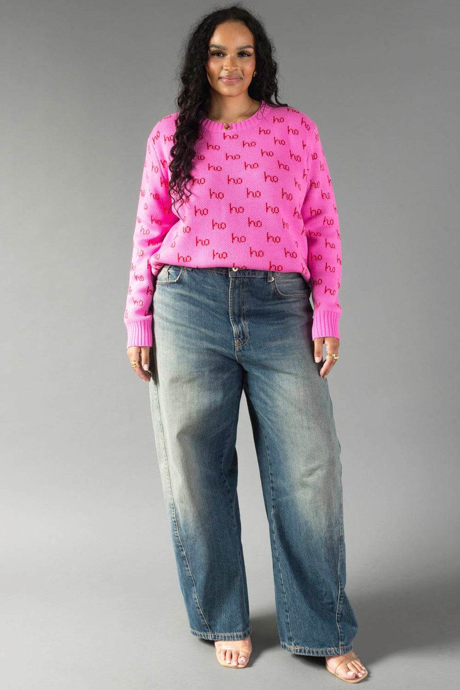 A person wearing a bright pink Pink Ho Ho Ho Sweater and wide-leg blue jeans.