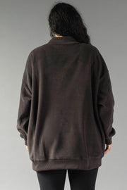 A person with long dark hair, seen from behind, wears the Panache Apparel Collection Dark Gray Game Day & Sunday Funday Reversible Sweatshirt and black pants against a plain gray background.