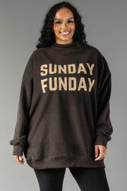 A woman smiles while wearing the Panache Apparel Collection Dark Gray Game Day & Sunday Funday Reversible Sweatshirt, featuring bold beige lettering, against a plain gray background.
